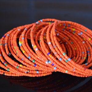 May include: A stack of orange beaded bracelets with small colorful beads interspersed throughout.