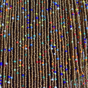 May include: A close-up of a beaded curtain with strands of gold-coloured beads interspersed with colourful beads in shades of blue, red, green, and white.