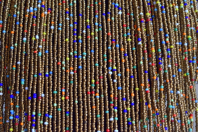 May include: A close-up of a beaded curtain with strands of gold-coloured beads interspersed with colourful beads in shades of blue, red, green, and white.