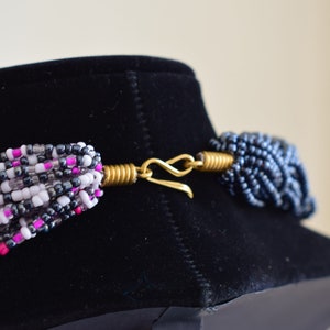May include: A multi-strand necklace with pink, white, and gray beads. The necklace has a gold clasp.