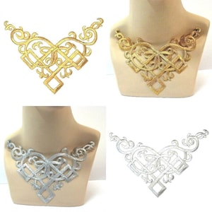 May include: A collection of four embroidered appliqués featuring a V-shaped design with intricate scrollwork and geometric patterns. Two appliqués are metallic gold and two are metallic silver, shown both flat and displayed on a mannequin neck.