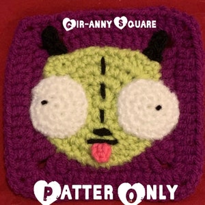 May include: Crocheted square featuring a green, purple, white, and pink character with large eyes and a tongue sticking out. The text "GIR-ANNY SQUARE PATTERN ONLY" is visible at the top and bottom of the square.