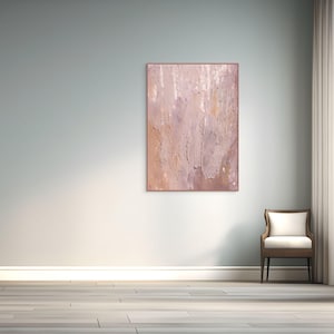 Puede incluir: Una pintura abstracta con una paleta de colores rosa y beige cuelga de una pared azul claro. La obra de arte está enmarcada en un marco delgado de color marrón claro. Una silla de madera con un cojín blanco está a la derecha.