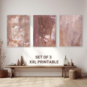Könnte beinhalten: Set aus drei XXL-Drucken abstrakter Kunst. Jedes gerahmte Kunstwerk zeigt ein strukturiertes, mehrschichtiges Design in Braun-, Beige- und Rosatönen. Der Text "SET OF 3 XXL PRINTABLE" ist unterhalb der Kunstwerke zu sehen.