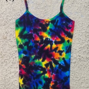 May include: A tie-dye tank top with a rainbow pattern on a black background. The tank top has a scalloped hem and thin straps.