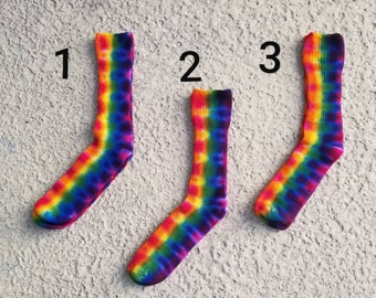 May include: Three pairs of colorful tie-dye socks with a rainbow pattern. The socks are numbered 1, 2, and 3.