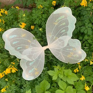 Op de afbeelding: Witte fee&euml;nvleugels met iriserende glitteraccenten. De vleugels zijn gemaakt van een dunne, delicate stof en hebben een vlindervorm.