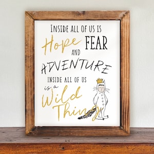 May include: A framed print with a white background and black text that reads "Inside all of us is Hope and Fear and Adventure. Inside all of us is a Wild Thing." The print features a black and white illustration of a character wearing a white suit with a crown and a tail.