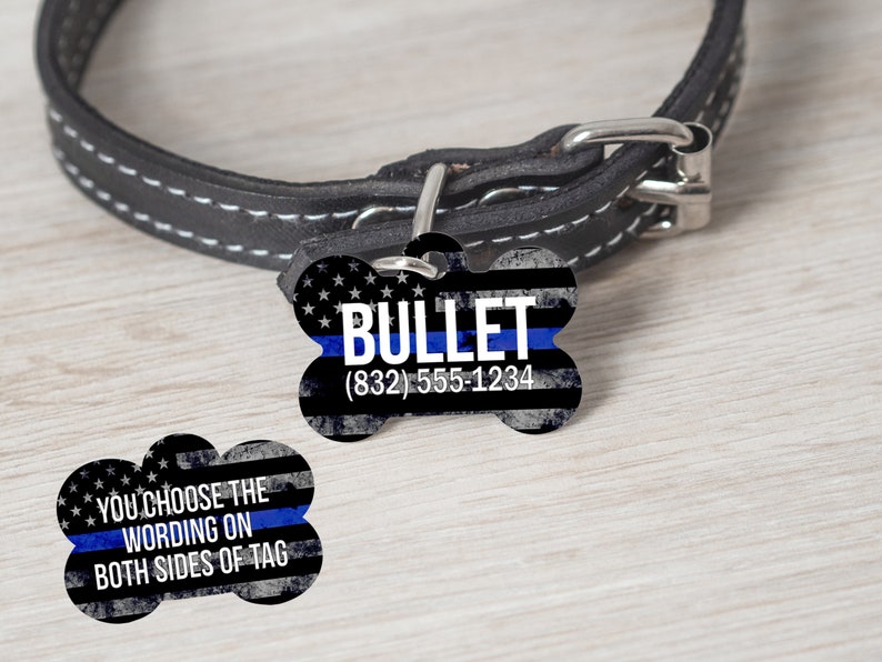 May include: A black leather dog collar with a bone-shaped dog tag. The tag has a blue line and an American flag design. The text on the tag reads "BULLET (832) 555-1234". The other side of the tag says "YOU CHOOSE THE WORDING ON BOTH SIDES OF TAG".