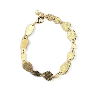 Può includere: Bracciale dorato con maglie strutturate di forma irregolare. Il bracciale ha una chiusura a moschettone e una catena regolabile. Le maglie variano per dimensioni e forma, creando un design unico. Il bracciale è esposto su sfondo bianco.
