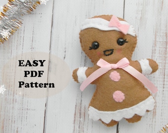 May include: A felt gingerbread girl ornament with a pink bow, white icing, and pink buttons. The ornament is on a white wooden background with silver tinsel and snowflakes. The text "EASY PDF Pattern" is on the left side of the image. The text "*Magic Pattern Shop*" is on the bottom right side of the image.
