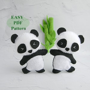 May include: Two felt panda plushies with black eyes and ears, standing on a white background. The pandas are holding a green felt bamboo stalk.