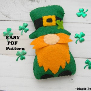 May include: A felt gnome wearing a green hat with a gold buckle and a shamrock. The gnome has an orange beard and is sitting on a white wooden surface. The text "EASY PDF Pattern" is visible in the image.