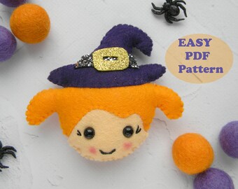 May include: A felt witch doll with orange hair, a purple hat with a gold buckle, and a smiling face. The doll is surrounded by purple and orange felt balls and black spiders. The text "EASY PDF Pattern" is written in a circle on the image.