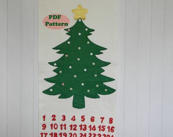 May include: A white felt Christmas tree advent calendar with a gold star on top. The numbers 1 through 24 are printed in red on the bottom of the tree. The text "PDF Pattern" is printed in black on the top of the tree.
