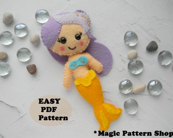 May include: A felt mermaid doll with purple hair, a blue and yellow top, and a yellow tail. The doll is on a white background with small white stones and glass beads. The text "EASY PDF Pattern" is on the bottom left of the image. The text "*Magic Pattern Shop*" is on the bottom right of the image.