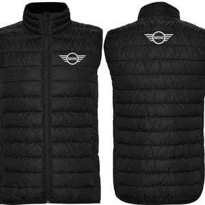 May include: Black quilted vest with a stand-up collar and a full-length zipper. The vest features the "MINI" logo on the chest and back. The vest is designed with a lightweight, puffy construction.