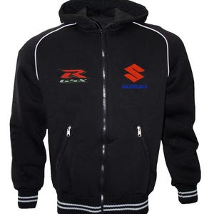 May include: Black zip-up hoodie with a hood and white trim. Features the Suzuki logo in red and blue on the chest, and a smaller GSX logo on the left side. The cuffs and waistband have white stripes.