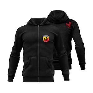 Może przedstawiać: Dwie czarne bluzy z kapturem zapinane na zamek. Jedna ma kolorowe logo na piersi i czerwony emblemat skorpiona na plecach. Druga bluza ma to samo logo na piersi. Obie bluzy mają kaptur i przednie kieszenie.