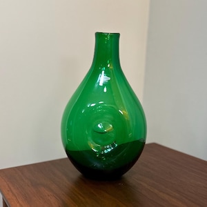 Può includere: Un vaso di vetro verde scuro con un design a spirale unico si trova su una superficie di legno.