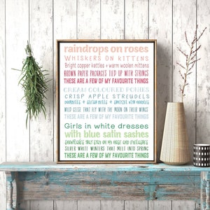 May include: A framed print with a white background and colourful text. The text reads "raindrops on roses, whiskers on kittens, bright copper kettles + warm woolen mittens, brown paper packages tied up with strings, these are a few of my favourite things, cream coloured ponies, crisp apple strudels, doorbells + sleigh bells + snitzels with noodles, wild geese that fly with the moon on their wings, these are a few of my favourite things, girls in white dresses with blue satin sashes, snowflakes that stay on my nose and eyelashes, silver white winters that melt into spring, these are a few of my favourite things."