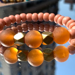 以下が含まれることがあります： 2つのブレスレット。1つはピーチ色のビーズ、もう1つはアンバー色のビーズとゴールドのスペーサーを使用しています。