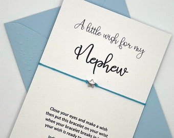 May include: A white card with blue text that reads "A little wish for my Nephew". A blue string bracelet with a silver star charm is attached to the card.