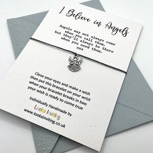 May include: A white card with black text that reads "I Believe in Angels" and a silver angel charm attached to a black string bracelet. The text on the card reads "Angels may not always come when you call them, but they'll always be there when you need them.  XXX Close your eyes and make a wish then put this bracelet on your wrist when your bracelet breaks in two your wish is ready to come true Individually Handmade by Looks Inviting www.looksinviting.co.uk"