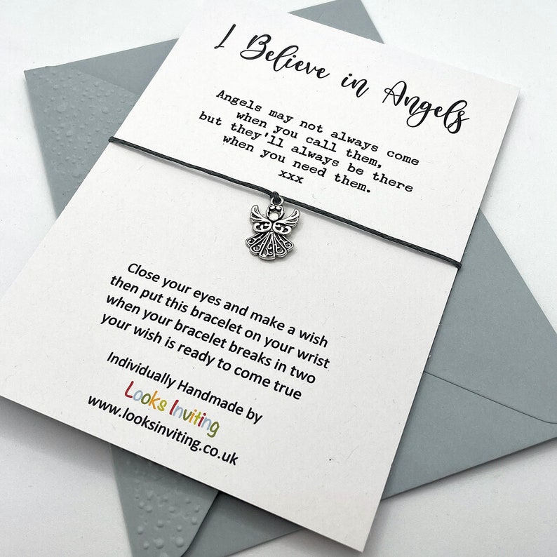 May include: A white card with black text that reads "I Believe in Angels" and a silver angel charm attached to a black string bracelet. The text on the card reads "Angels may not always come when you call them, but they'll always be there when you need them.  XXX Close your eyes and make a wish then put this bracelet on your wrist when your bracelet breaks in two your wish is ready to come true Individually Handmade by Looks Inviting www.looksinviting.co.uk"