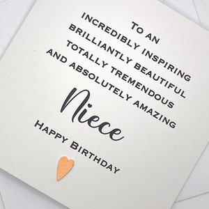 Puede incluir: Una tarjeta blanca con texto negro que dice "To an incredibly inspiring brilliantly beautiful totally tremendous and absolutely amazing Niece Happy Birthday". Un peque&ntilde;o coraz&oacute;n dorado se encuentra en la esquina inferior derecha.