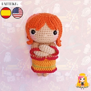 Puede incluir: Muñeca amigurumi de crochet con ropa roja y naranja. La muñeca tiene el pelo naranja, ojos marrones y una tez marrón claro. La muñeca está de pie con los brazos cruzados.