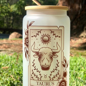 Vaso de vidrio esmerilado con tapa de bambú y pajita, con la carta del tarot del zodíaco Tauro
