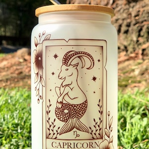 Vaso de vidrio esmerilado con tapa de bambú y pajita, con la carta del tarot del zodíaco Capricornio