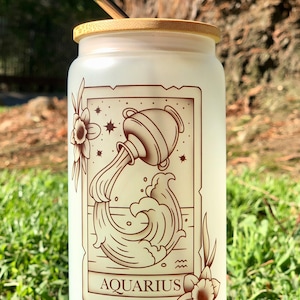 Vaso de vidrio esmerilado con tapa de bambú y pajita con la carta del tarot del zodíaco Acuario