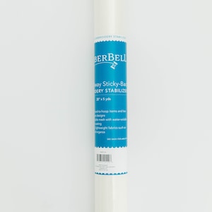 May include: A white roll of 20 inch by 5 yard  "Sticky-Back" embroidery stabilizer from the brand "Berbell". The label is blue with white text and a small needle and thread icon. The label says "Sticky-Back Embroidery Stabilizer" and "20" x 5 yds".