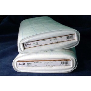 Puede incluir: Dos rollos de tela de rejilla para acolchado Bosal, estilo #327, apilados. La tela es blanca con un patrón de rejilla azul claro. Cada rollo está etiquetado con el logotipo de Bosal e información del producto, incluyendo un ancho de 122 cm y 22.86 metros.