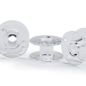 Puede incluir: Tres bobinas de plástico transparente para una máquina de coser.