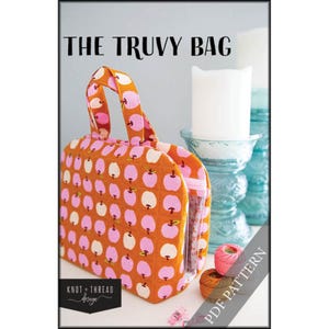 May include: An orange fabric bag with a pink and white apple pattern. The bag has a clear plastic side and a handle. The text "THE TRUVY BAG" is at the top. The words "PDF PATTERN" are on a diagonal.