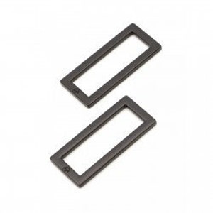 May include: Two dark grey metal belt loops with rounded corners are shown against a white backdrop. Each loop features a small, embossed detail in one corner. These rectangular loops are suitable for crafting or garment construction.