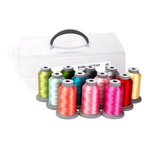 Può includere: Una custodia di plastica trasparente con manico nero contiene 12 bobine di filo Glide in vari colori. Le bobine sono disposte a semicerchio, mostrando sfumature di verde, rosa, rosso e giallo. Il testo "GLIDE THREAD KIT" è visibile.