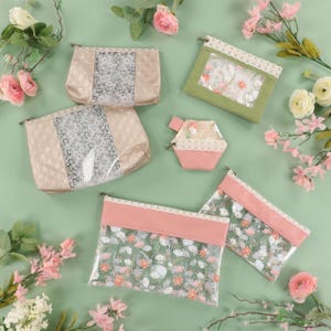 May include: A collection of six pouches in various sizes and shapes, featuring metallic gold, sage green, and dusty pink faux leather accents, clear panels with floral patterns, and white lace trim along the top edges of each zippered bag.