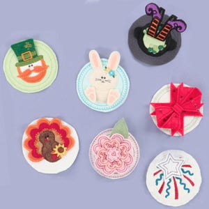 Puede incluir: Una colección de posavasos de fieltro con varios diseños festivos y de temporada. Incluye un duende, un conejito, piernas de bruja, un lazo rojo, un pavo, una flor y fuegos artificiales. Cada posavasos es redondo con costuras decorativas.