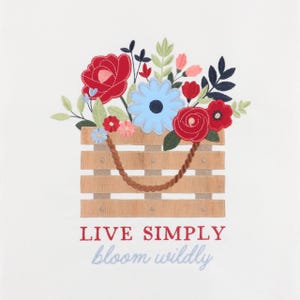 May include: An embroidered graphic on a white background featuring a light brown wooden crate with a rope handle, filled with red, light blue, and pink flowers and green leaves. The text reads "LIVE SIMPLY" in red and "bloom wildly" in light blue.