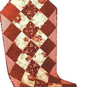 May include: A red and white patchwork table runner with a floral pattern. The runner is made of squares and has a diamond pattern.