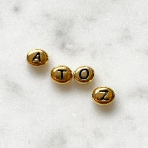 Cuentas del alfabeto, bañadas en oro, Tierra Cast
