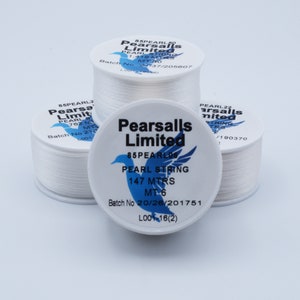 May include: Three spools of white pearl string, each with a label that reads "Pearsails Limited" and includes the length of the string in meters. The label on the front spool reads "85PEARL06 PEARL STRING 147 MTRS MT 6 Batch No 20/26/201751 L001-16(2)"