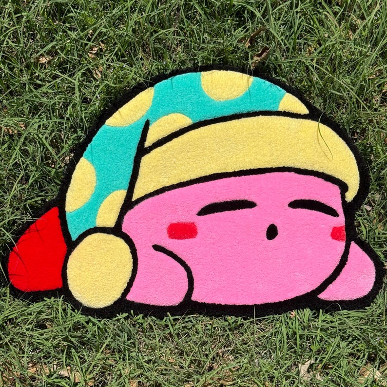 May include: A pink and blue plush rug shaped like a sleeping cartoon character wearing a blue and yellow hat.