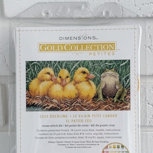 May include: A Dimensions Gold Collection cross stitch kit featuring the "Ugly Duckling." The kit includes pre-sorted thread, an 18-count ivory Aida cloth, a needle, and instructions. The finished size is 8 x 4 inches.