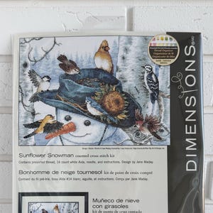 Op de afbeelding: Een Dimensions kruissteekpakket met een sneeuwman met een hoed versierd met zonnebloemen en vogels. De kit bevat voorgesorteerd garen, 14-count witte Aida, een naald en instructies. Het voltooide ontwerp meet 35,5 cm x 25,4 cm.