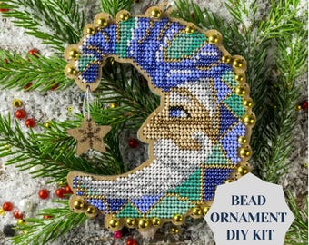 May include: A crescent moon-shaped bead ornament DIY kit featuring a blue and green beaded design with a gold star charm. The kit includes all the beads and instructions needed to create the ornament.